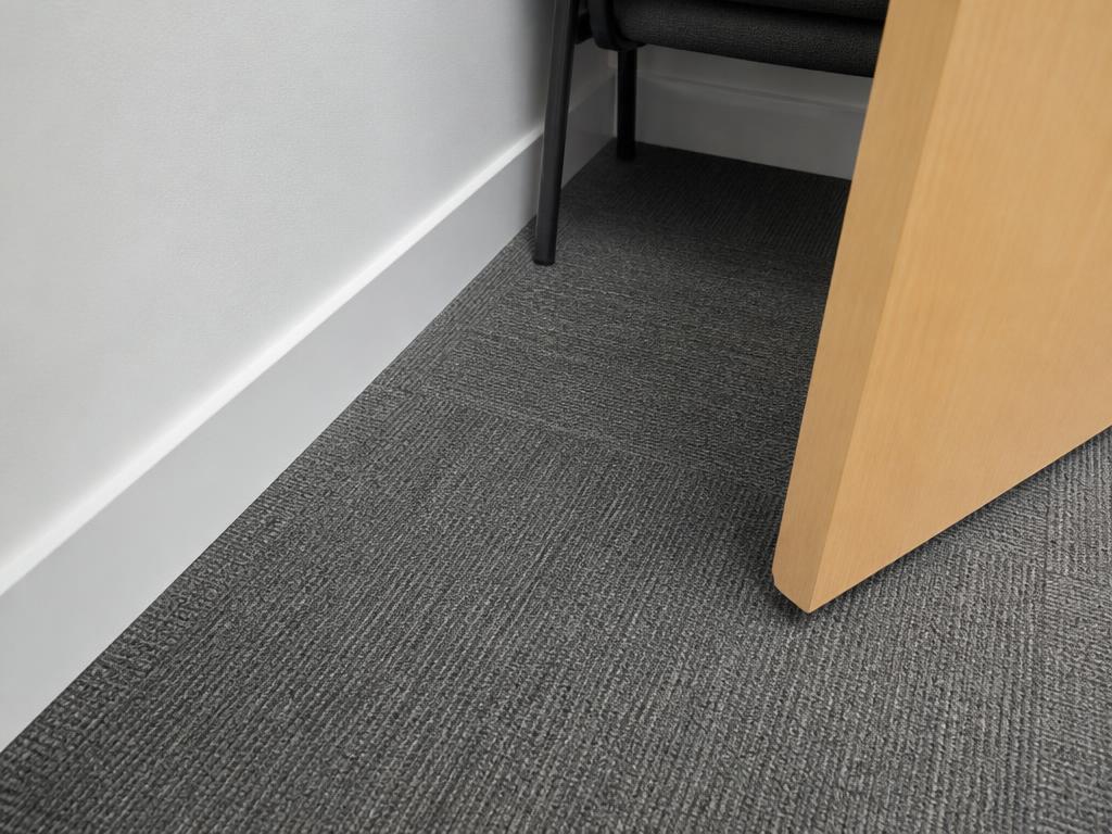 The same meeting room floor edge from the same angle, now fully clean along the skirting board